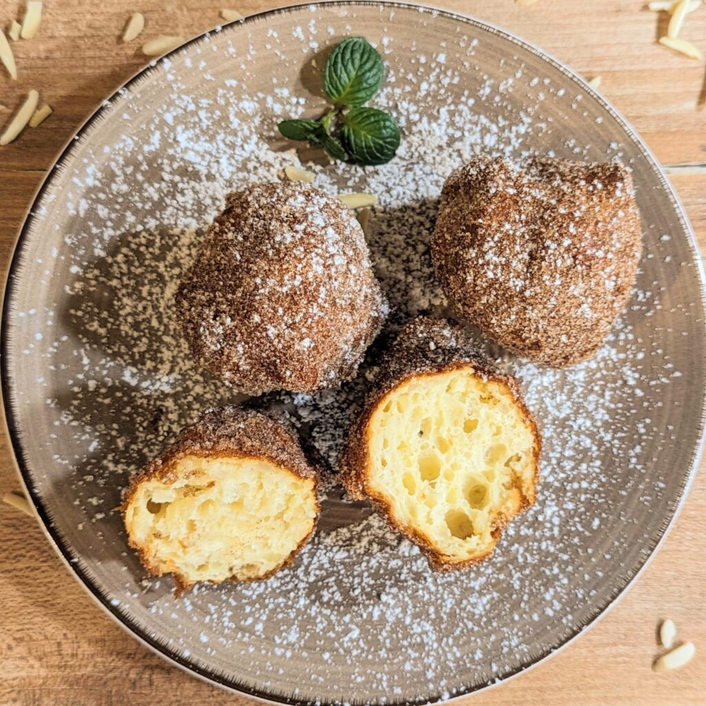 Ein Teller mit mehreren teilweise angeschnittenen Krapfen.