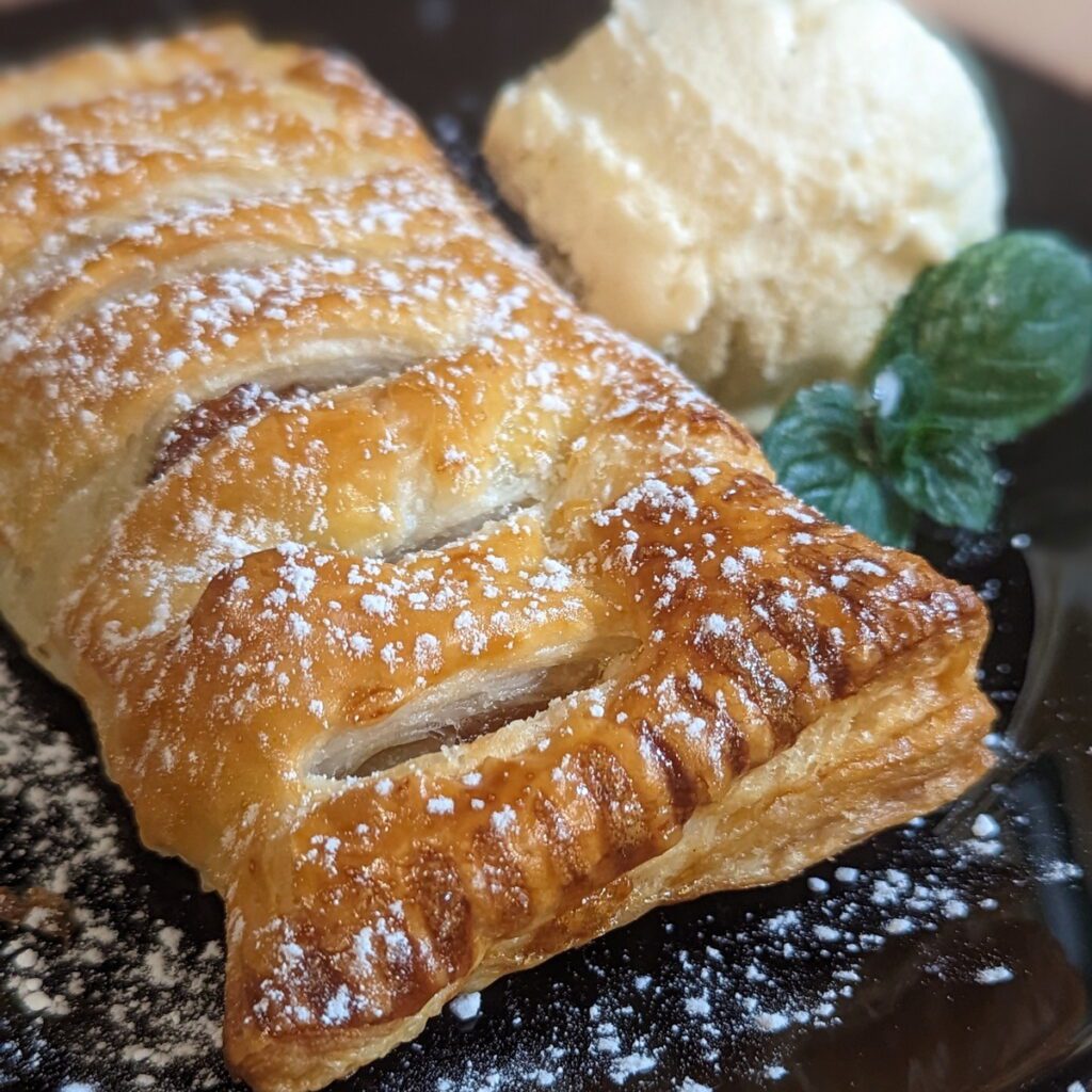 Knusprige warme Apfeltasche mit einer Kugel Vanilleeis auf einem teller