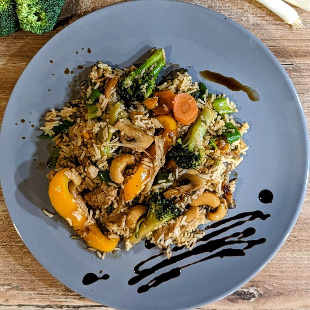Ein Teller asiatische Reispfanne mitPaprika, Brokkoli,Cashew und Möhren