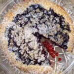 Eine Blaubeer Tart auf einer Servierplatte, dekoriert mit Roten Johannisbeeren