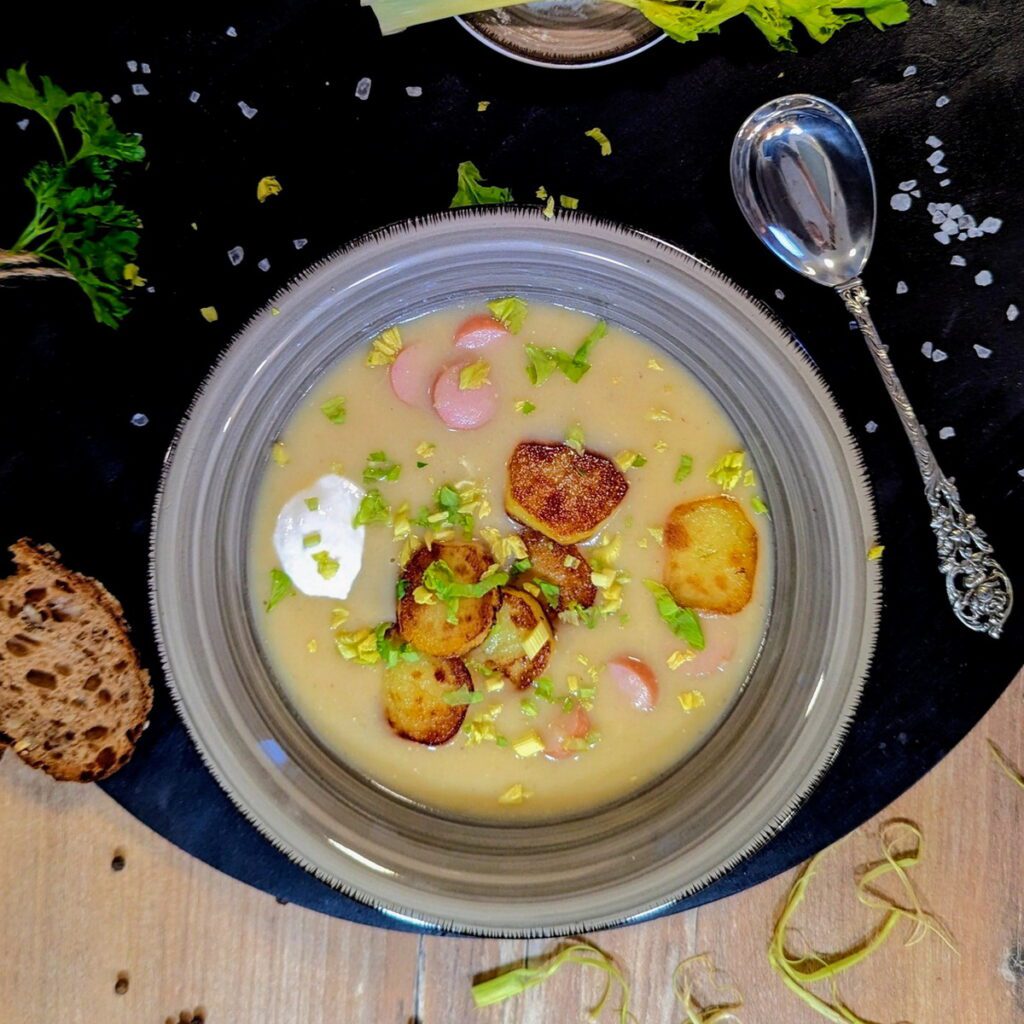 Ein Teller Bratkartoffel-Suppe mit angerösteten Kartoffeln und einem Klecks Creme Fraiche