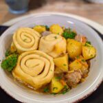 Ein Teller mit Dampfnudeln Strudel auf Kartoffel, Fleisch und Sauerkraut