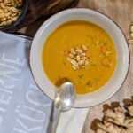 Ein Teller mit cremiger Erdnuss-Suppe, garniert mit gerösteten Erdnüssen
