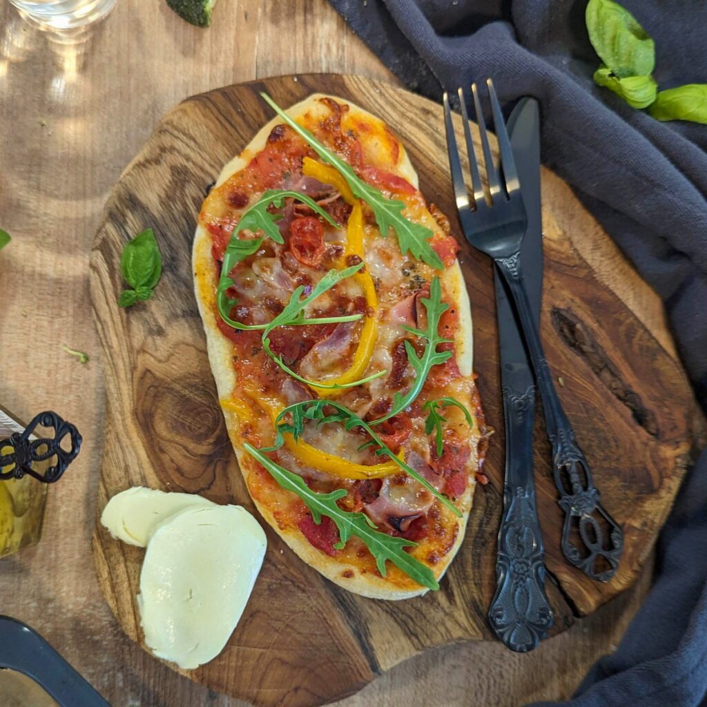 Kleines Pizzaboot, Minipizza, belegt mit Schinken, Paprika und Rocola