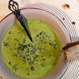 Ein Teller mit heißer Kresse-Erbsen-Suppe, angerichtet mit frischer Kresse und Brot
