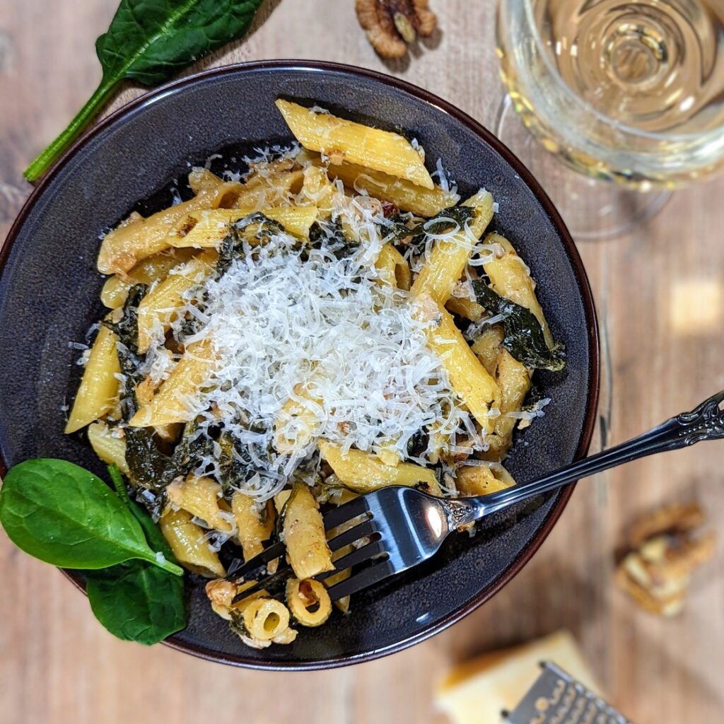 Ein Teller mit Pasta mit Babyspinat und Walnüssen,, bestreut mit frischem Parmesan