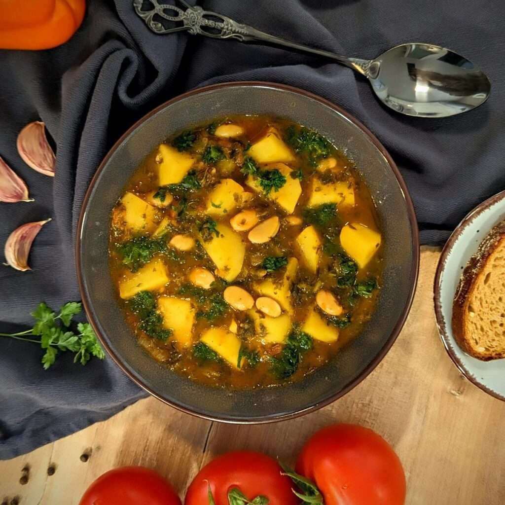 Ein Teller mit winterlichem Gemüseeintopf mit Grünkohl, Kartoffeln und weiße Bohnen